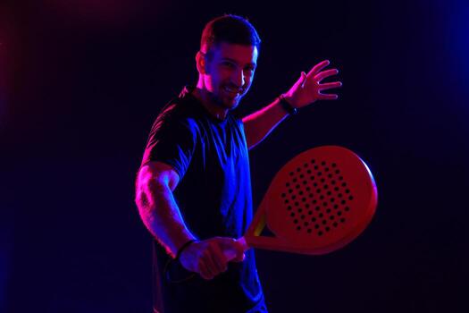 Man playing paddle tennis with a bright racket in a colorful setting photo