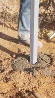securing posts in concrete accurately, precisely positioning and leveling metal post for stable installation, ensuring accurate and level installation of metal posts into concrete foundation video