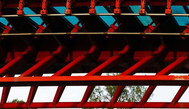 Red and blue roller coaster rail with geometric patterns and trees in background photo