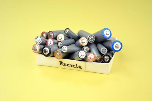 A lot of Used AA batteries and proper disposal of environmentally and soil toxic batteries on a green background. photo