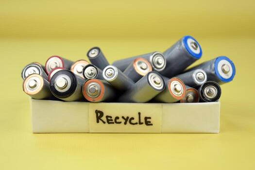 More Used AA batteries and proper disposal of environmentally and soil toxic batteries on a green background photo