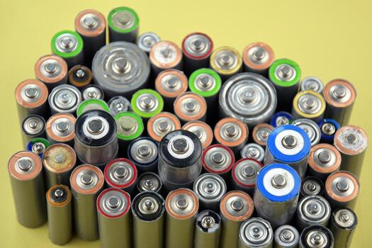 More Used AA batteries and proper disposal of environmentally and soil toxic batteries on a green background. photo