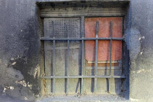 Basement window metal grate closed by material plates. Rusty, red and holey sheets in the wings photo