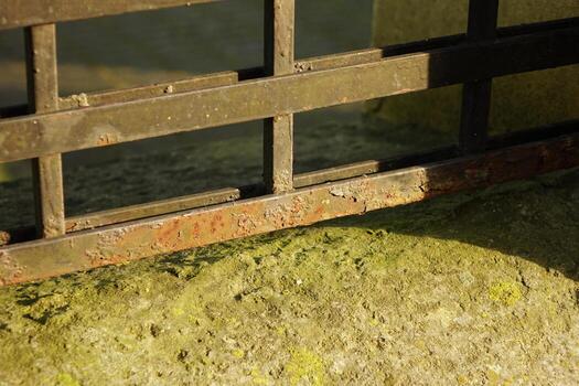 The iron fence made of plates at the bottom of the aisle is rusty with paint residue in sunny weather photo