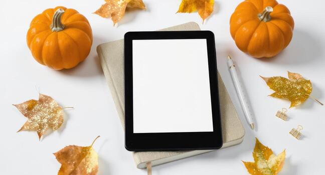 Flat lay showing tablet notebook pen pumpkins leaves on white surface for fall season photo