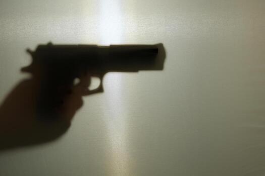 Shadowy outline of a pistol aimed forward on a matte background photo