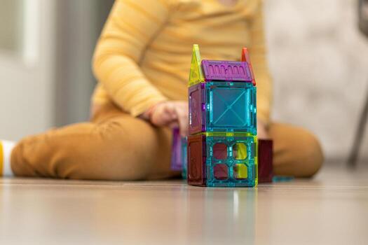 Child creating a colorful structure with magnetic building blocks indoors in a cozy environment photo