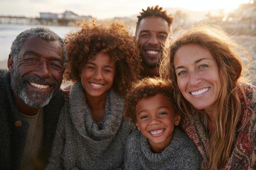 Family group portrait featuring diverse individuals with joyful expressions, wearing cozy sweaters, enjoying a sunny beach setting, capturing warmth and togetherness in a beautiful moment photo