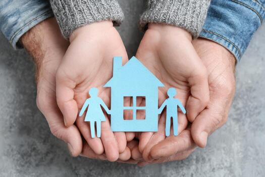 Hands of diverse individuals holding blue paper cutouts of a house and figures representing family, symbolizing unity, love, and the concept of home and belonging in a nurturing environment photo