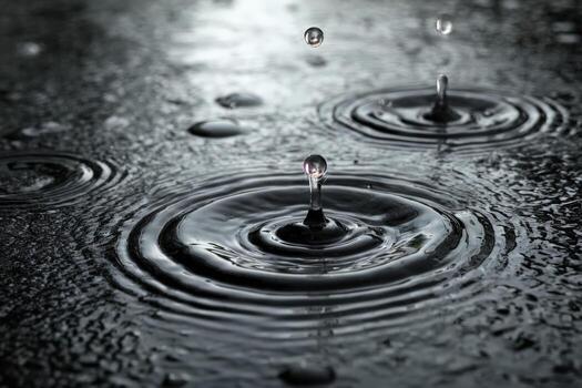 de cerca de agua gotas creando ondas en un oscuro superficie, exhibiendo el belleza de de la naturaleza elementos y el intrincado patrones formado por que cae lluvia foto