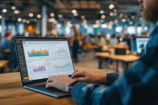 Professional man analyzing data on laptop in modern office environment, showcasing graphs and charts on screen, illustrating business analytics and productivity photo