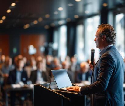 Businessman speaking at a conference, engaging audience with microphone in hand, illuminated by soft lighting, showcasing professional public speaking and communication skills photo