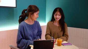 Due ragazza alunno godere il rilassato atmosfera di bar mentre collaboratore su loro Università incarichi, loro siamo utilizzando tavoletta e Appunti, discutere idea e condivisione intuizioni per loro progetto video