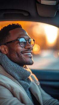 Man Smiling While Sitting in a Car With Warm Sunset Colors in the Background photo