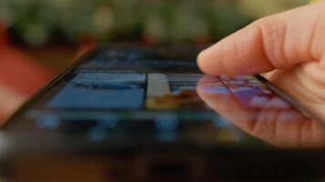 smartphone finger rullning pekskärm med mjuk jul lampor lysande i suddig bakgrund, visa upp digital förbindelse under festlig kväll video