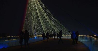 Menschen Gehen auf ein dekoriert Brücke beim das Weihnachten Markt im das Park aus von Fokus Urlaub Hintergrund. Licht Bokeh von Weihnachten Baum. Neu Jahr Thema, Hintergrund. video