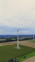 Wind turbines on the background of large fields. Aerial view of wind turbines and agricultural fields. Wind turbines generate electricity video