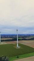 Wind turbines on the background of large fields. Aerial view of wind turbines and agricultural fields. Wind turbines generate electricity, green energy. Vertical video