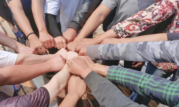 High-angle close-up shot of a diverse group of people stacking their fists together in a circle, symbolizing unity, teamwork, and power. Concept of collaboration, partnership, and success. photo