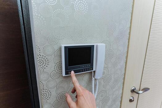 apartment intercom button being pressed, individual uses intercom to request entry at residential photo