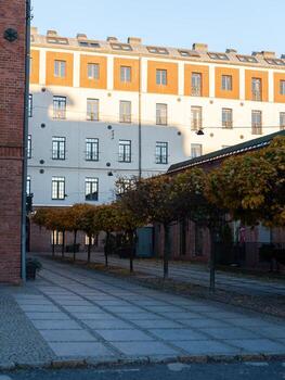 A brick building with a white facade and a row of trees in front of it photo