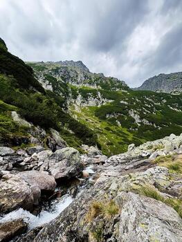 Stunning mountain landscape in Zakopane Poland with rocky cliffs and flowing stream beneath dramatic clouds photo
