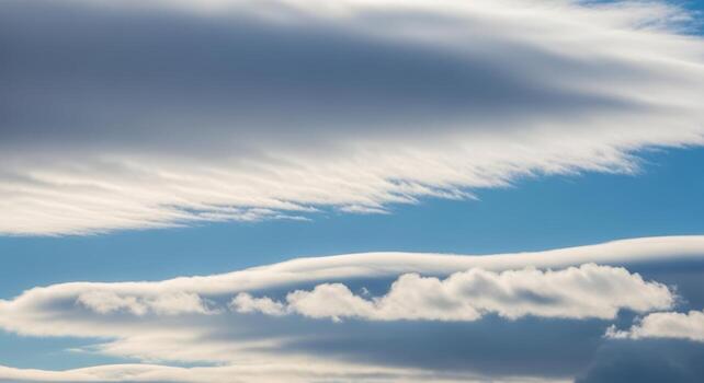 Layers of serene white and grey clouds formations floating across a vast and vibrant blue sky backdrop photo