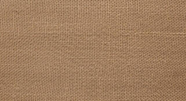 Close-up overhead view of a brown woven burlap fabric background with a visible coarse texture photo