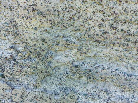 A close-up shows a concrete texture with a high concentration of colorful pebbles and stones exposed on its rough surface. This is a prominent example of exposed aggregate concrete. photo
