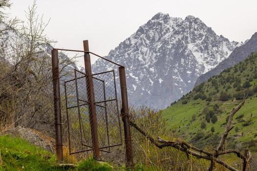 Rusty chain link fence with rotating gate in mountains of Kyrgyzstan. This gate is keeping cattle from passing, but leaving a way for people. photo