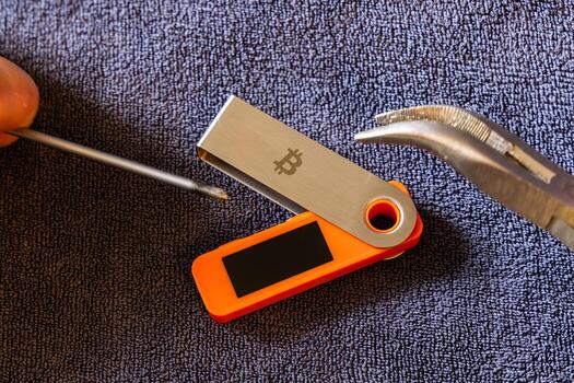 Hardware wallet being physically attacked indoors using screwdriver and pliers. Physical device vulnerability concept. photo