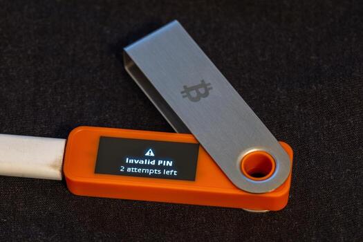 Close-up view of hardware security key displaying an error message indicating invalid PIN with two attempts left. Tense atmosphere captured on dark fabric surface during daytime. photo