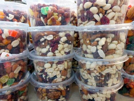 Assorted Nuts and Dried Fruits in Clear Plastic Containers at a Market Stall Display photo