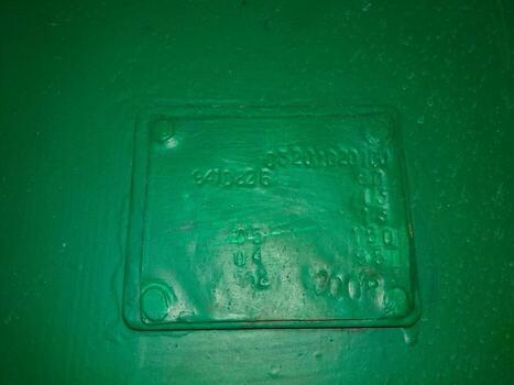 A Green Surface Features a Rectangular Sign With Embossed Text Indicating Identification Details photo