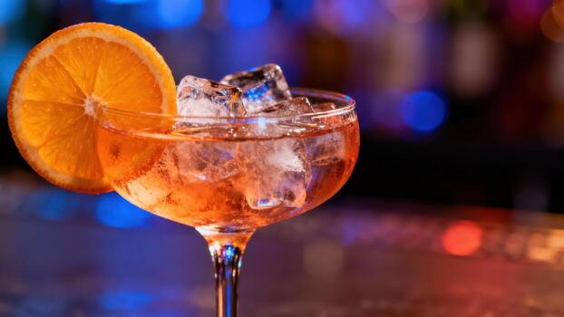 Refreshing chilled beverage garnished with a citrus slice sits prominently in a dimly lit setting photo