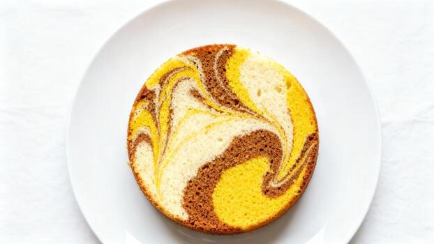 Round slice of marbled sponge dessert sits centered on a plain white plate viewed from directly above photo