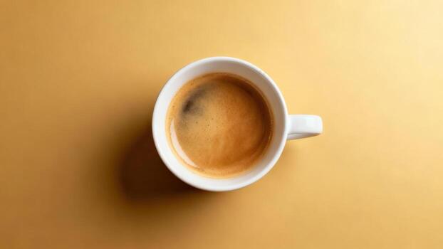 Overhead view captures freshly brewed espresso in a white ceramic cup resting on a plain surface photo
