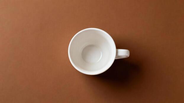Empty white ceramic drinking vessel positioned above a rich brown surface viewed from directly above photo