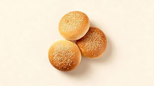 Three freshly baked round bread rolls sprinkled with sesame seeds are positioned on a light surface photo