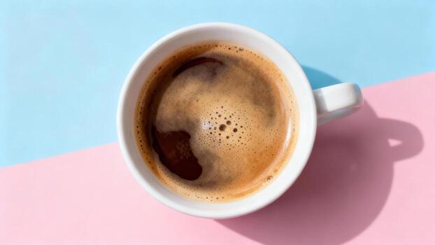 Hot beverage with frothy top rests on a surface divided by contrasting pastel colors photo