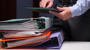 A man in a suit holding a tablet computer and a stack of binders video
