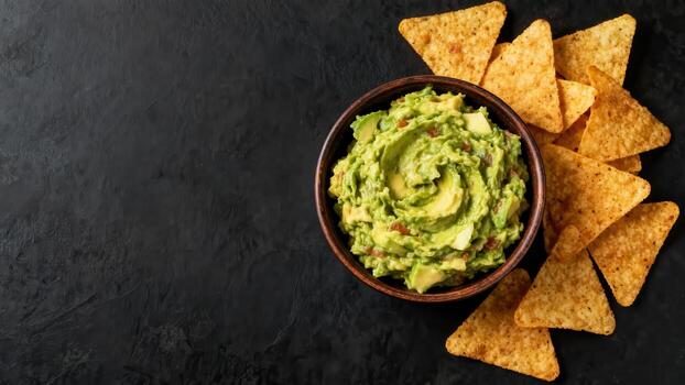 Creamy avocado dip served with crispy corn triangles on a dark surface photo