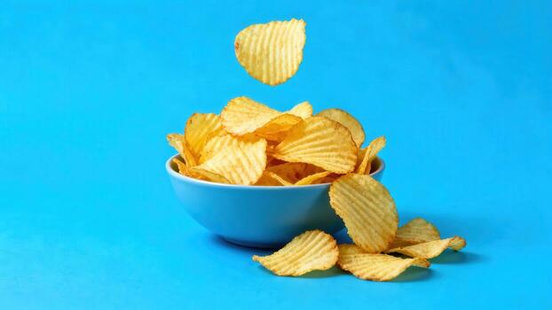 Rippled potato slices are dropping into a brightly colored ceramic container photo