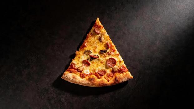 A single slice of delicious pepperoni and mushroom pizza rests on a dark surface. photo