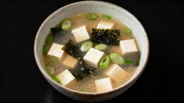 Savory fermented soybean paste broth contains cubed soft protein and green onion pieces photo