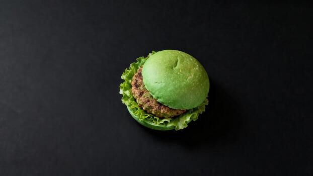 Gourmet sandwich creation featuring a unique green bun rests on a dark, plain surface viewed from above photo