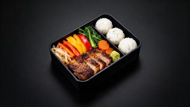 Prepared grilled meat and rice portions are neatly arranged inside a dark compartmentalized meal container photo