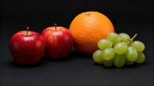Group of fresh red apples, one orange, and a bunch of green grapes displayed against a dark background photo