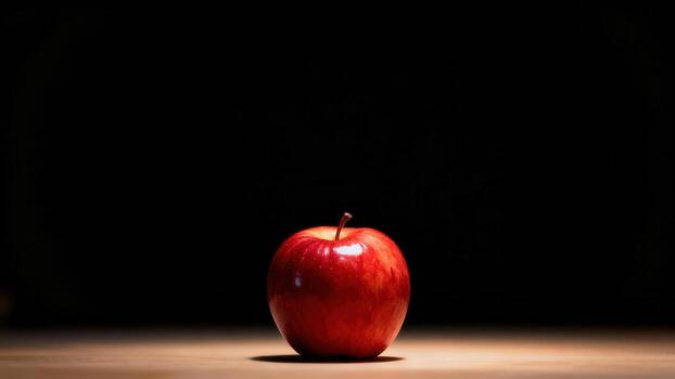 Vibrant red fruit sits illuminated against a deep black background photo