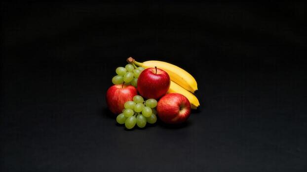 Assortment of fresh fruit including bananas, red apples, and green grapes arranged on a dark surface photo